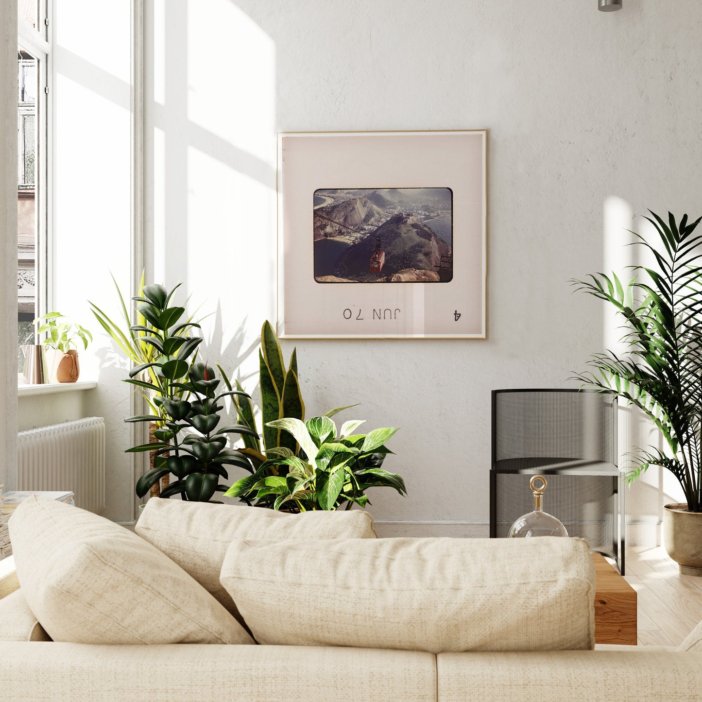 a cozy living room with a large window, a beige sofa, and a framed picture of a mountain landscape hanging on the wall.