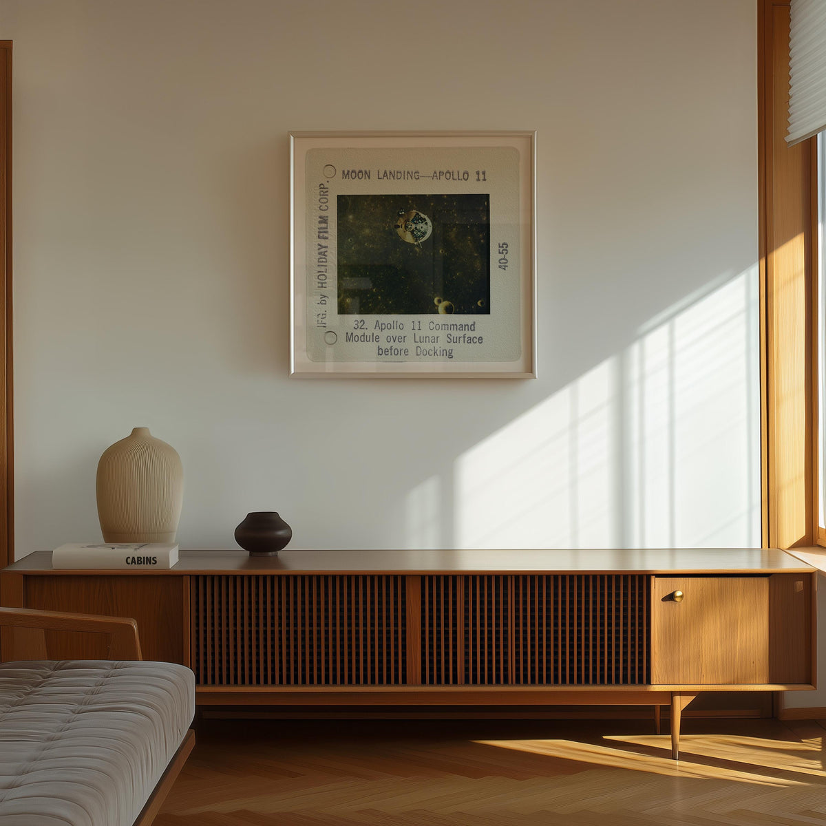 a framed photograph of the Apollo 11 moon landing, with the text "Moon Landing - Apollo 11" and "32. Apollo 11 Console before docking" visible. The photograph is mounted on a white wall above a wooden cabinet or entertainment center.