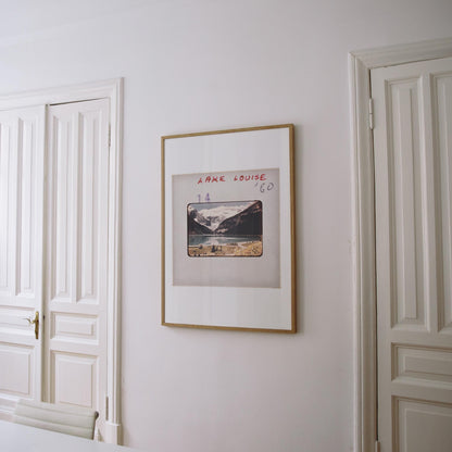 a framed photograph of a mountain landscape hanging on a white wall.