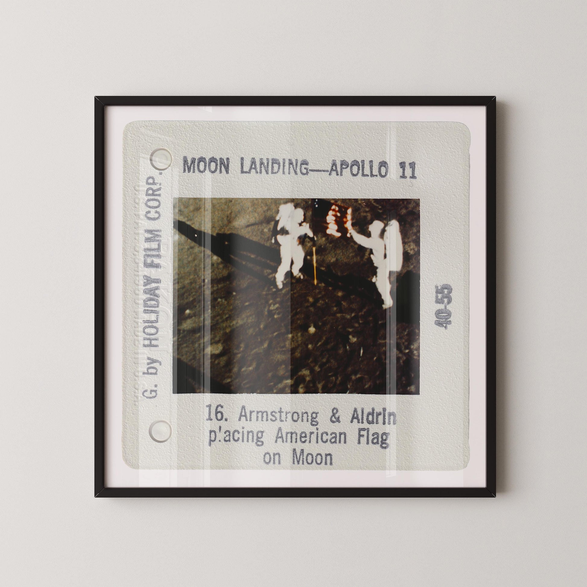 The image is a framed photograph of two people in white suits standing on the moon's surface, with the text "Moon Landing - Apollo 11" and "16. Armstrong & Aldrin p'acting American Flag on Moon" visible.