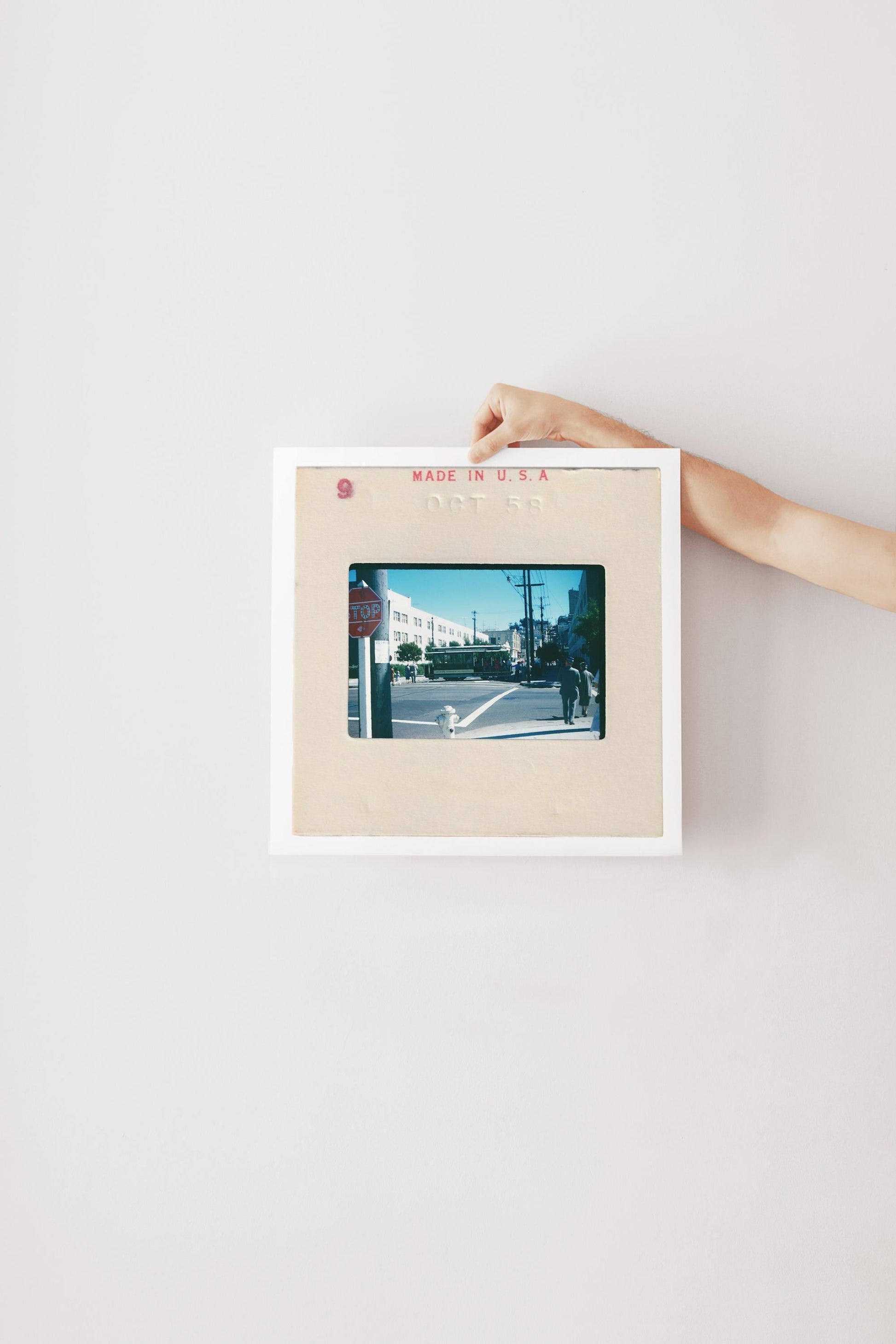 Vintage 1958 Kodachrome slide photograph of a San Francisco cable car passing through a sunny city intersection, with pedestrians in period dress, a red stop sign, utility poles, and a bright blue autumn sky. Printed as a giclée fine art print on archival matte paper.