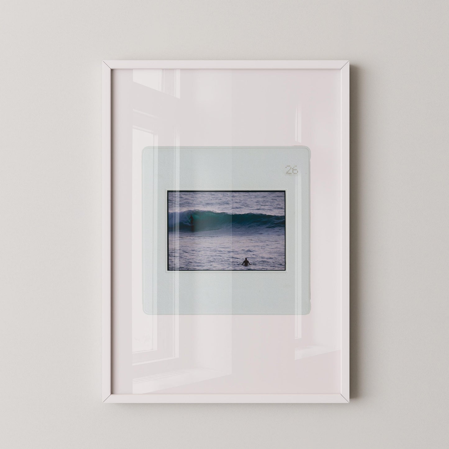 Vintage slide photograph of two surfers in the ocean — one riding a glassy teal-green wave in the background and one waiting chest-deep in silver-grey water in the foreground, shot with a telephoto lens from shore. Printed as a giclée fine art print on archival matte paper.