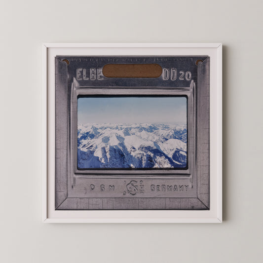 The image is a framed photograph of a snowy mountain landscape, with the text "ELB" and "0020" visible on the frame.
