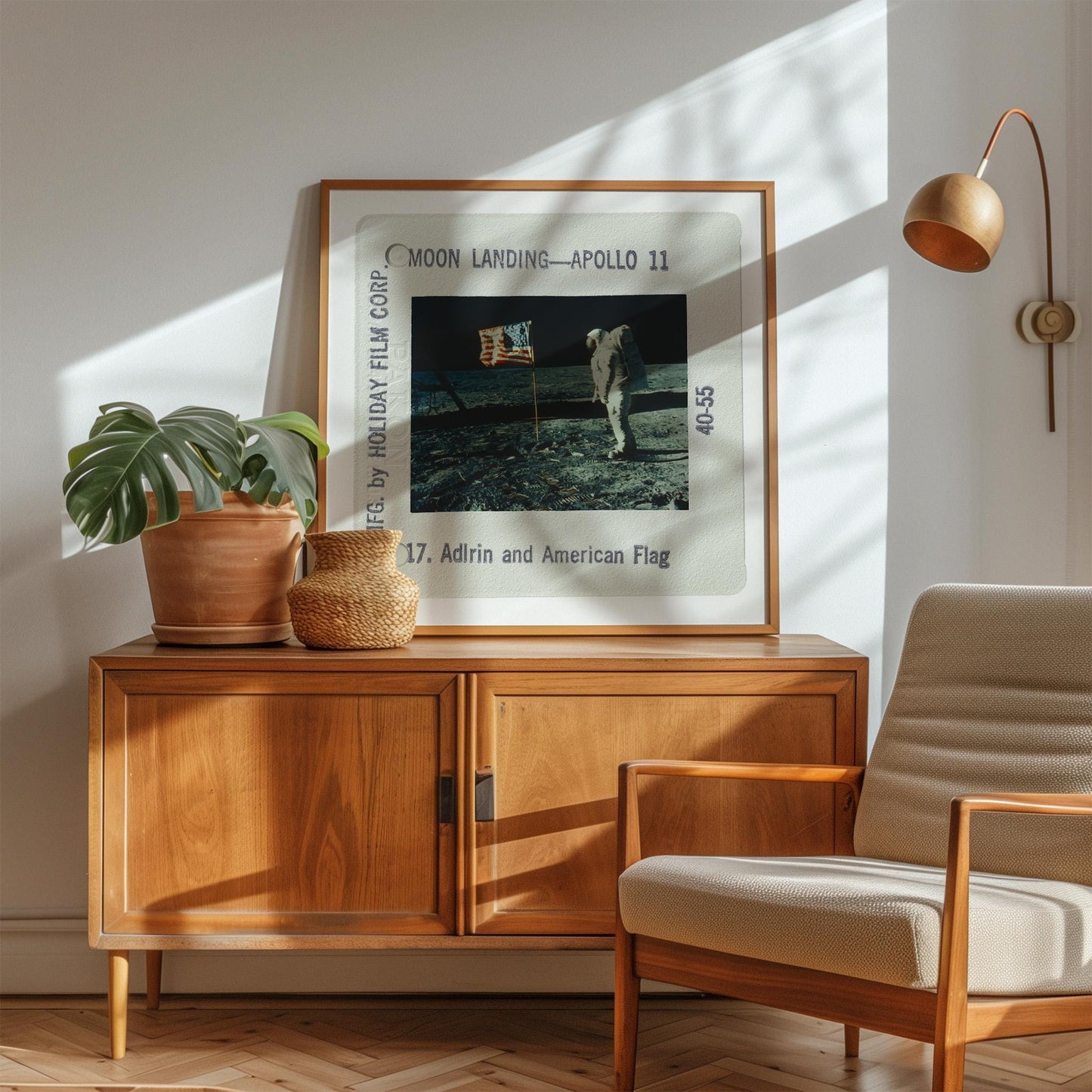 a framed photograph of the Apollo 11 moon landing, with a wooden cabinet and a beige armchair in the foreground.