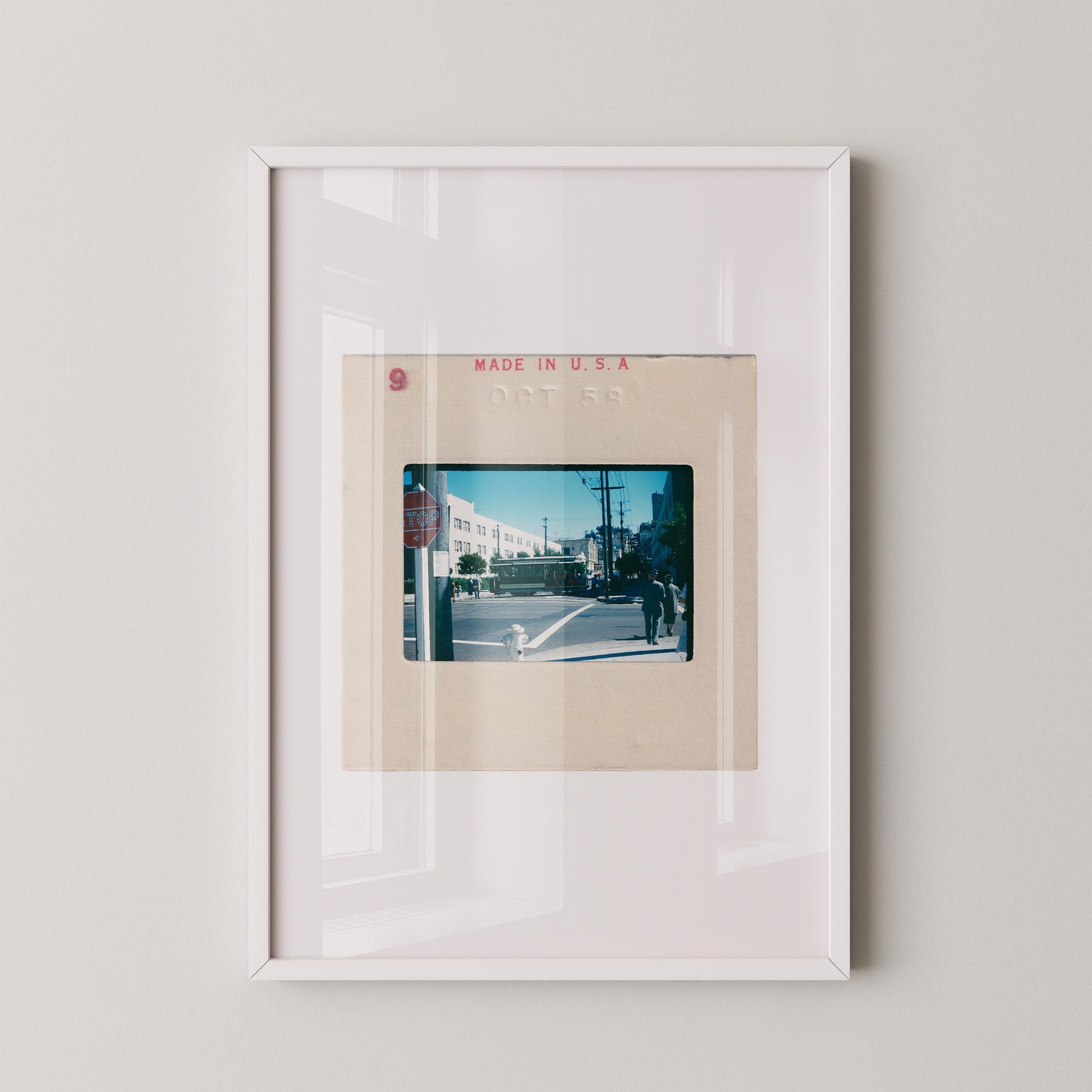 Vintage 1958 Kodachrome slide photograph of a San Francisco cable car passing through a sunny city intersection, with pedestrians in period dress, a red stop sign, utility poles, and a bright blue autumn sky. Printed as a giclée fine art print on archival matte paper.