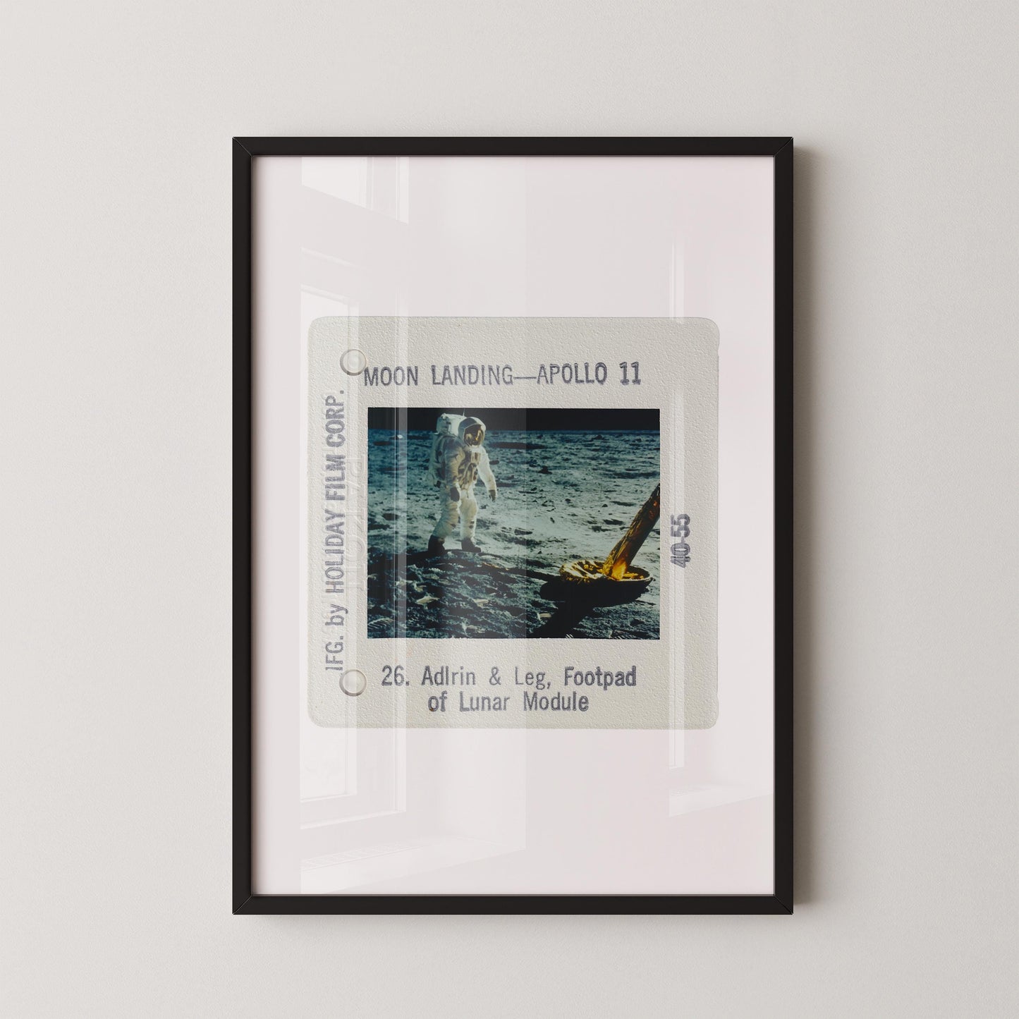 The image is a framed photograph of an astronaut walking on the surface of the moon, with a yellow spacecraft visible in the background.