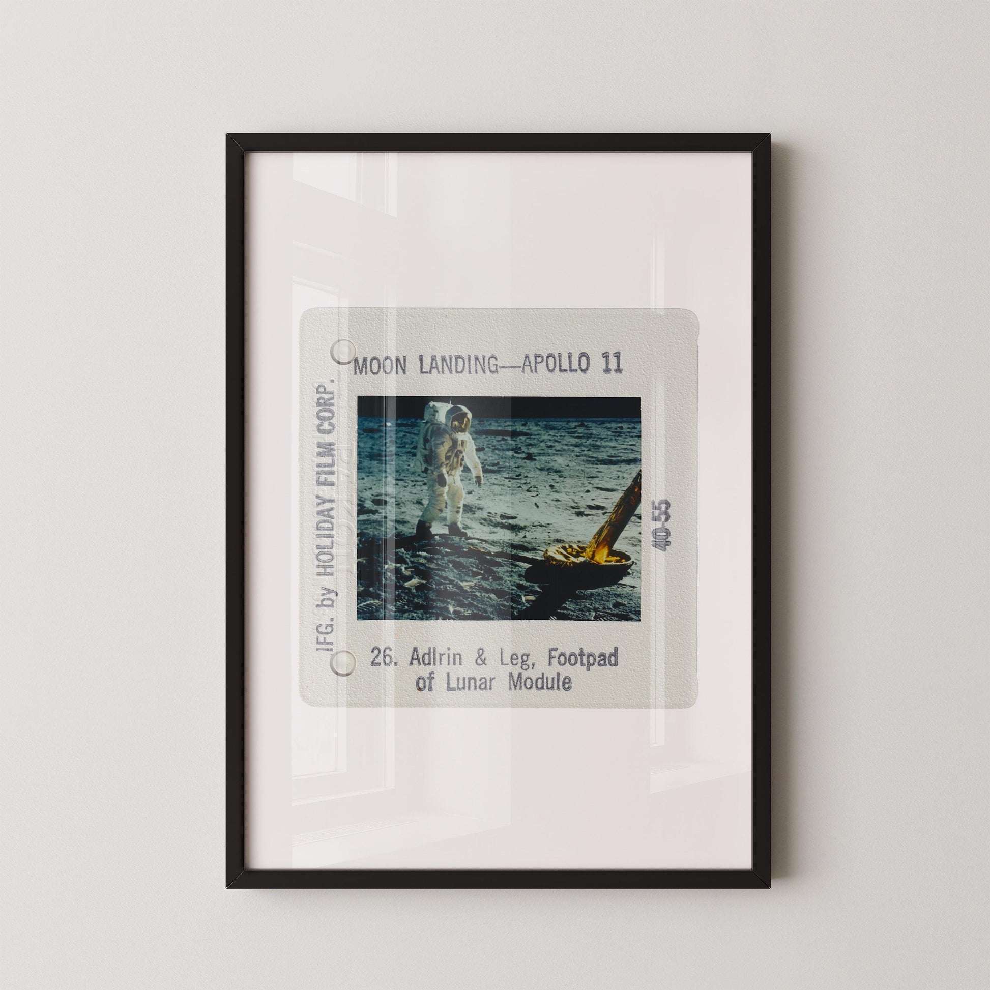The image is a framed photograph of an astronaut walking on the surface of the moon, with a yellow spacecraft visible in the background.