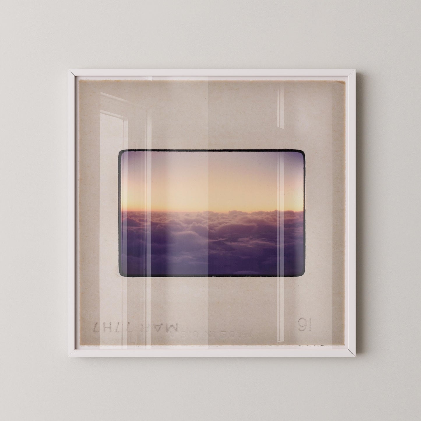 The image is a framed photograph of a sunset over a cloudy sky, with the sun setting behind the clouds.