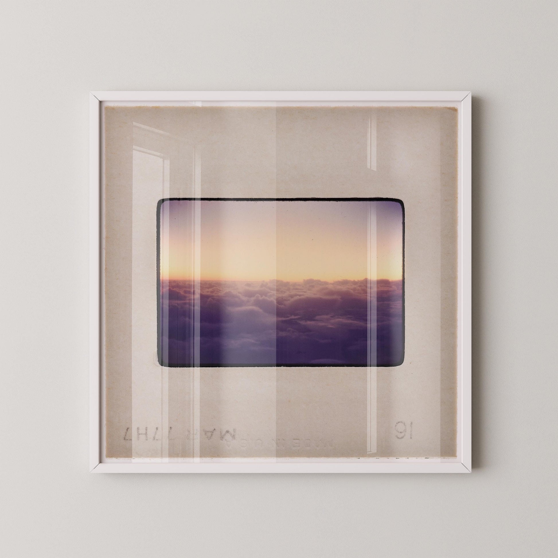 The image is a framed photograph of a sunset over a cloudy sky, with the sun setting behind the clouds.
