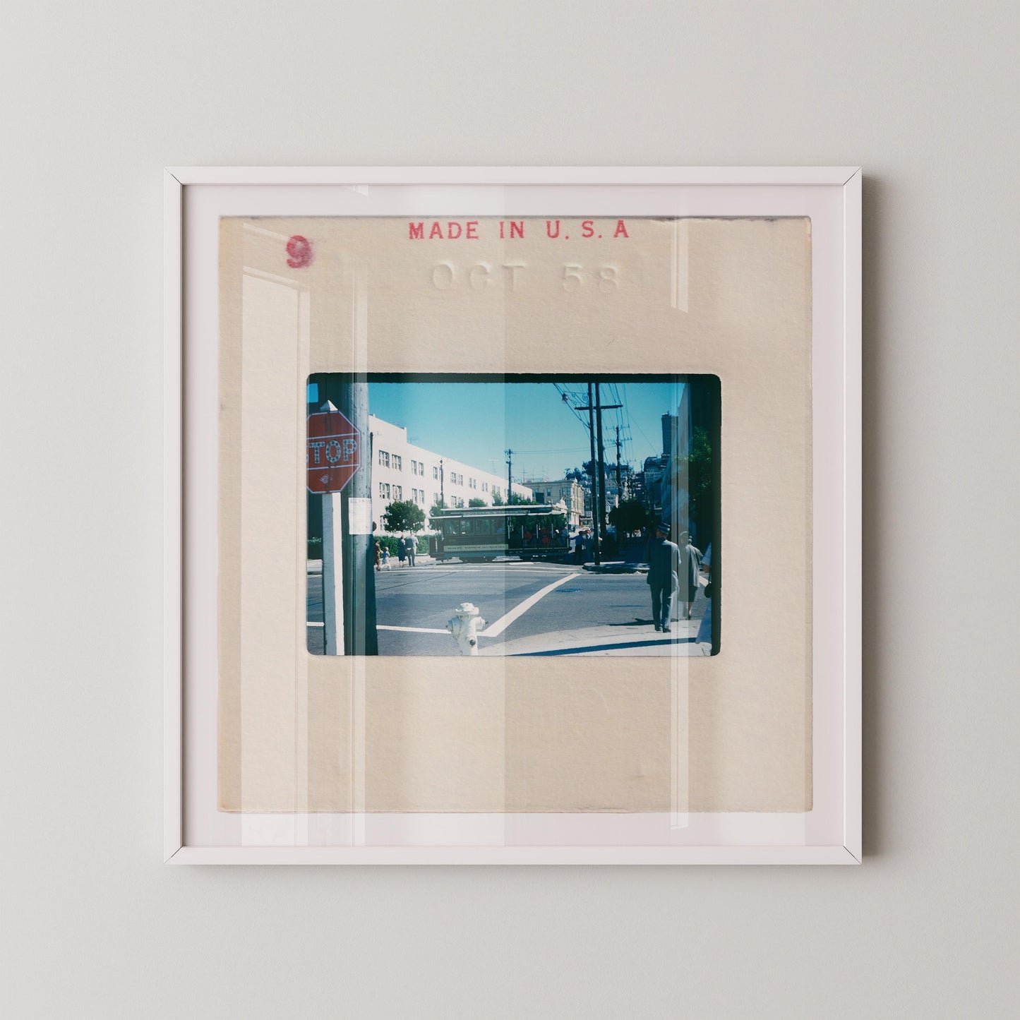 Vintage 1958 Kodachrome slide photograph of a San Francisco cable car passing through a sunny city intersection, with pedestrians in period dress, a red stop sign, utility poles, and a bright blue autumn sky. Printed as a giclée fine art print on archival matte paper.