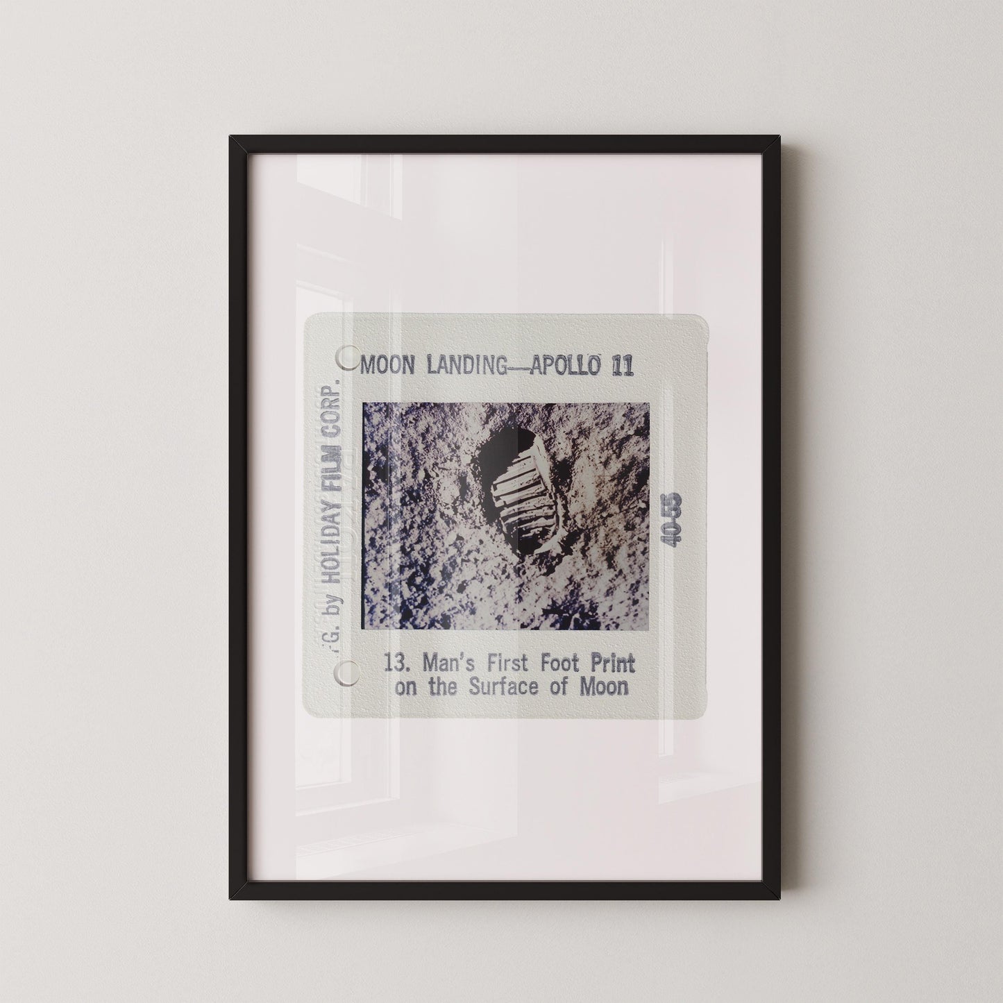 The image is a framed photograph of a man's first footprint on the surface of the moon, taken during the Apollo 11 mission.