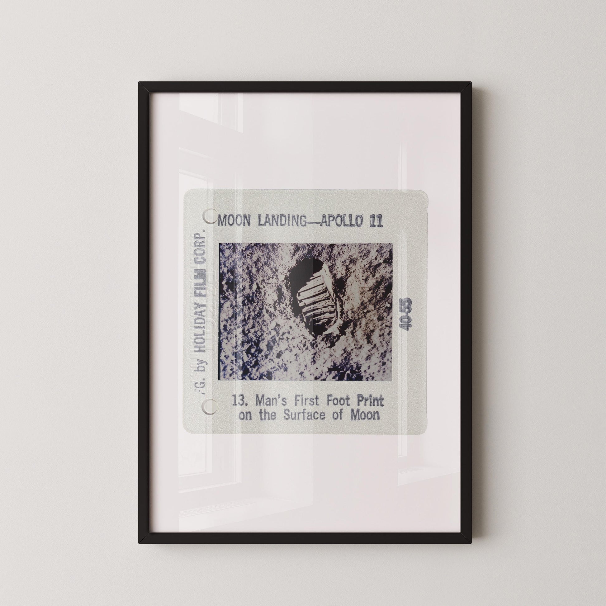 The image is a framed photograph of a man's first footprint on the surface of the moon, taken during the Apollo 11 mission.