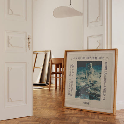 a framed photograph of the Apollo 11 moon landing, with the text "F.G. by HOLIDAY FILM CORP. MOON LANDING - APOLLO 11" visible on the frame.
