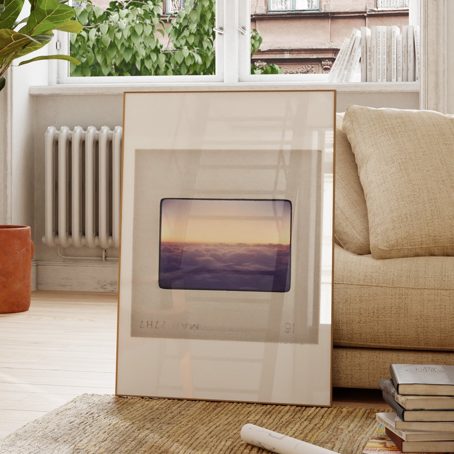 a framed photograph of a sunset over a body of water, placed on a wooden floor in a living room setting.
