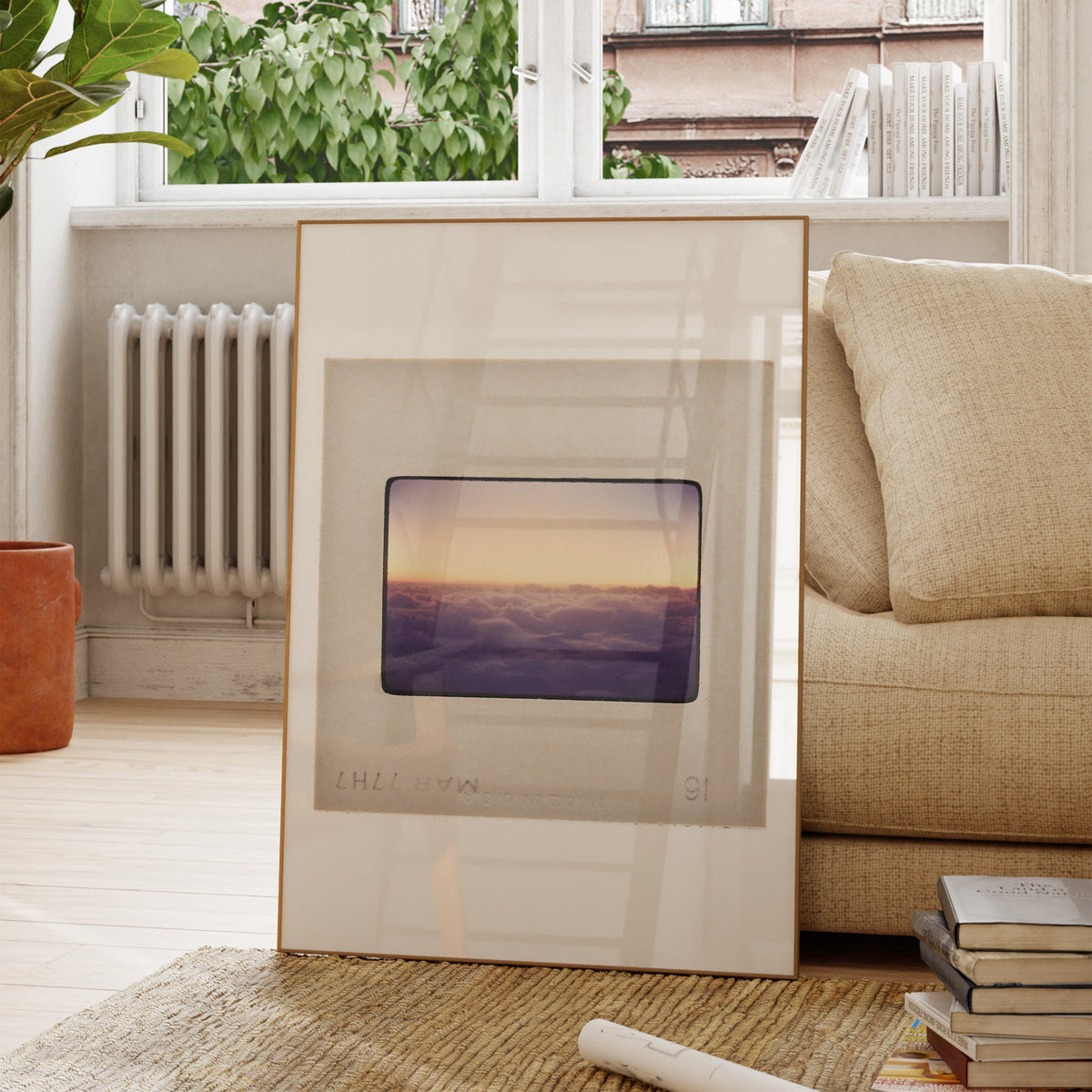 a framed photograph of a sunset over a body of water, placed on a wooden floor in a living room setting.