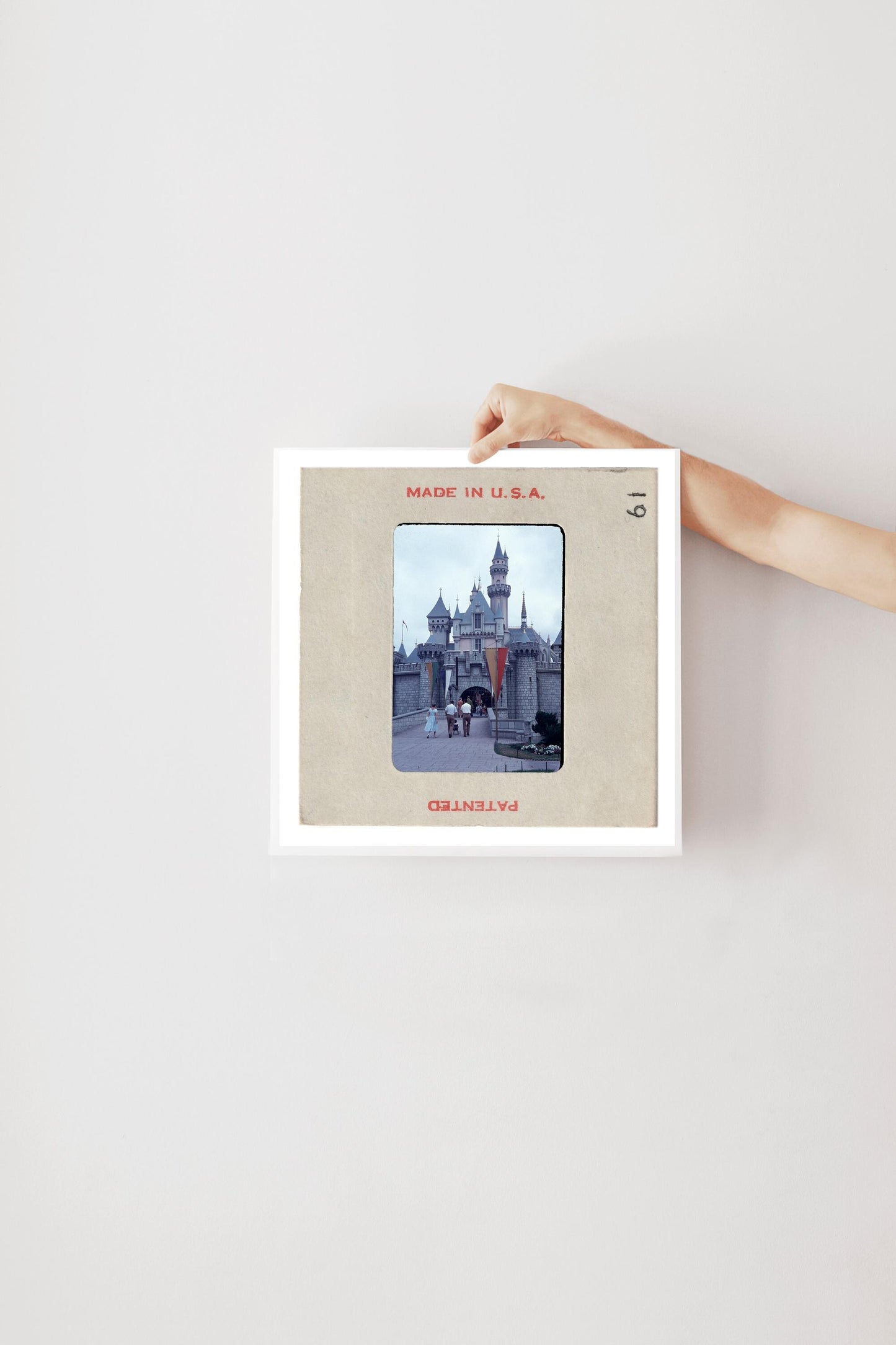 A person's hand is holding a framed picture of a castle or palace, with the text "MADE IN U.S.A." visible on the frame.