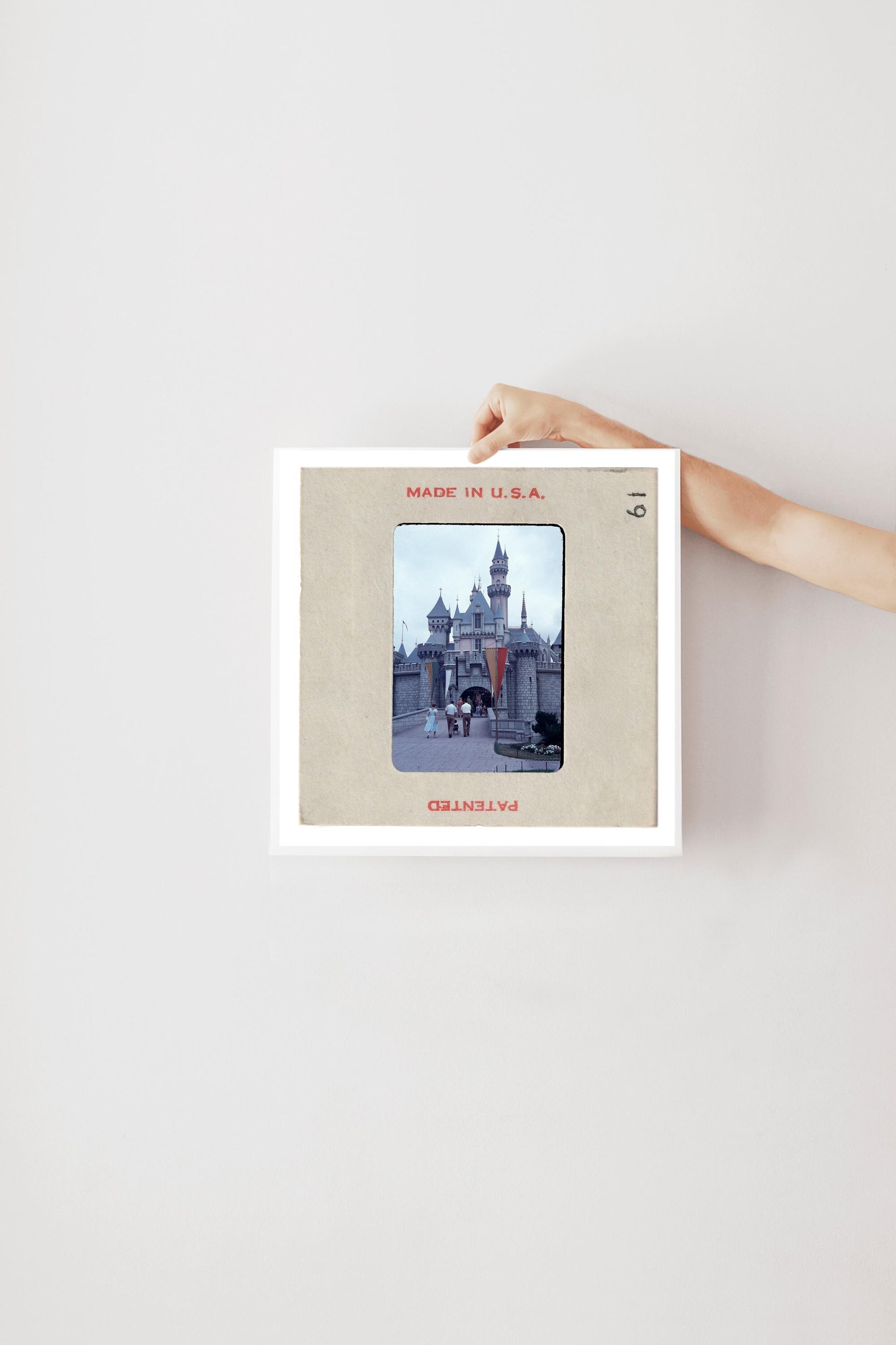 A person's hand is holding a framed picture of a castle or palace, with the text "MADE IN U.S.A." visible on the frame.