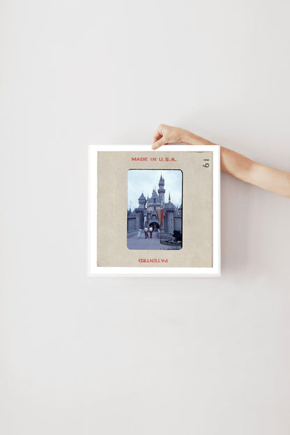 A person's hand is holding a framed picture of a castle or palace, with the text "MADE IN U.S.A." visible on the frame.