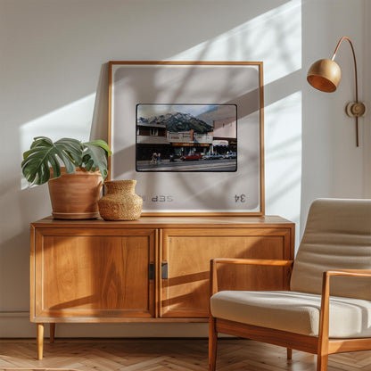 a cozy living room with a wooden cabinet, a comfortable chair, and a framed picture of a building with a mountain in the background.