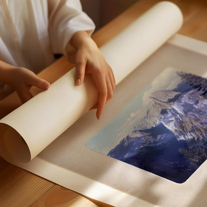 A person's hands are holding a roll of paper over a printed image of a mountain landscape.