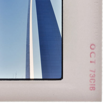 a close-up view of a white frame with a blue and white striped structure, possibly a building or monument, reflected in it.