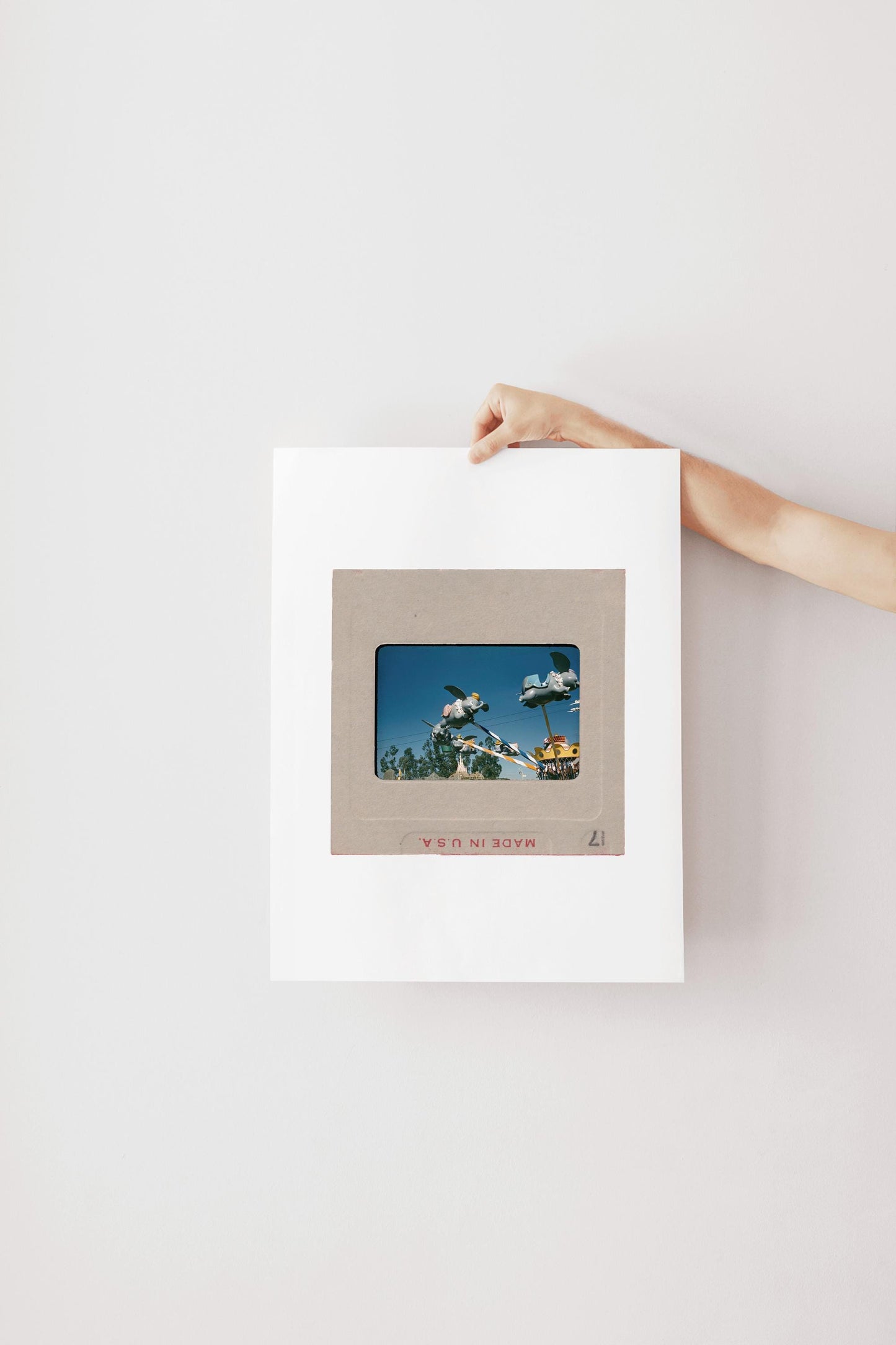 A person's hand is holding a white frame with a framed photograph inside it, which appears to be a collage of multiple images.