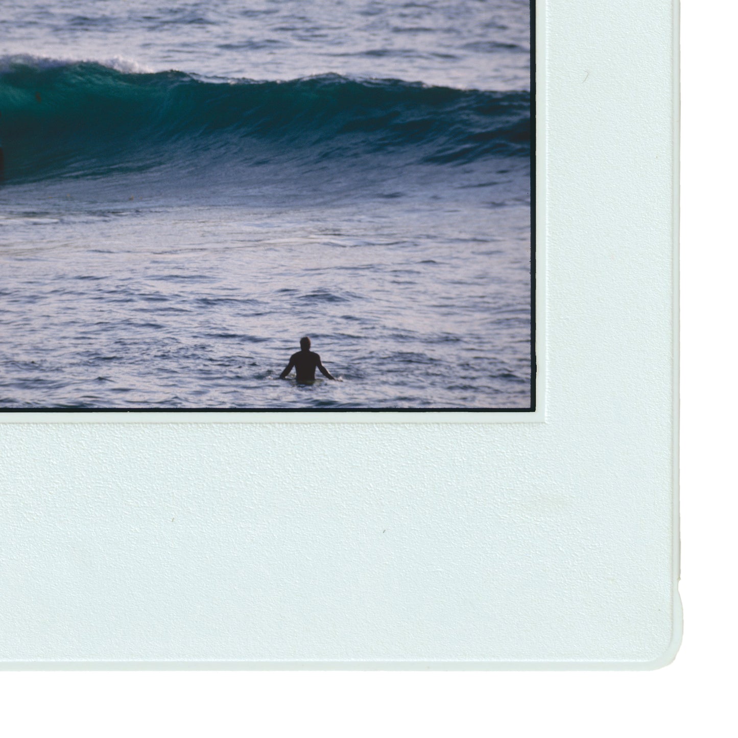 A person is seen swimming in the ocean, with a large wave crashing behind them.
