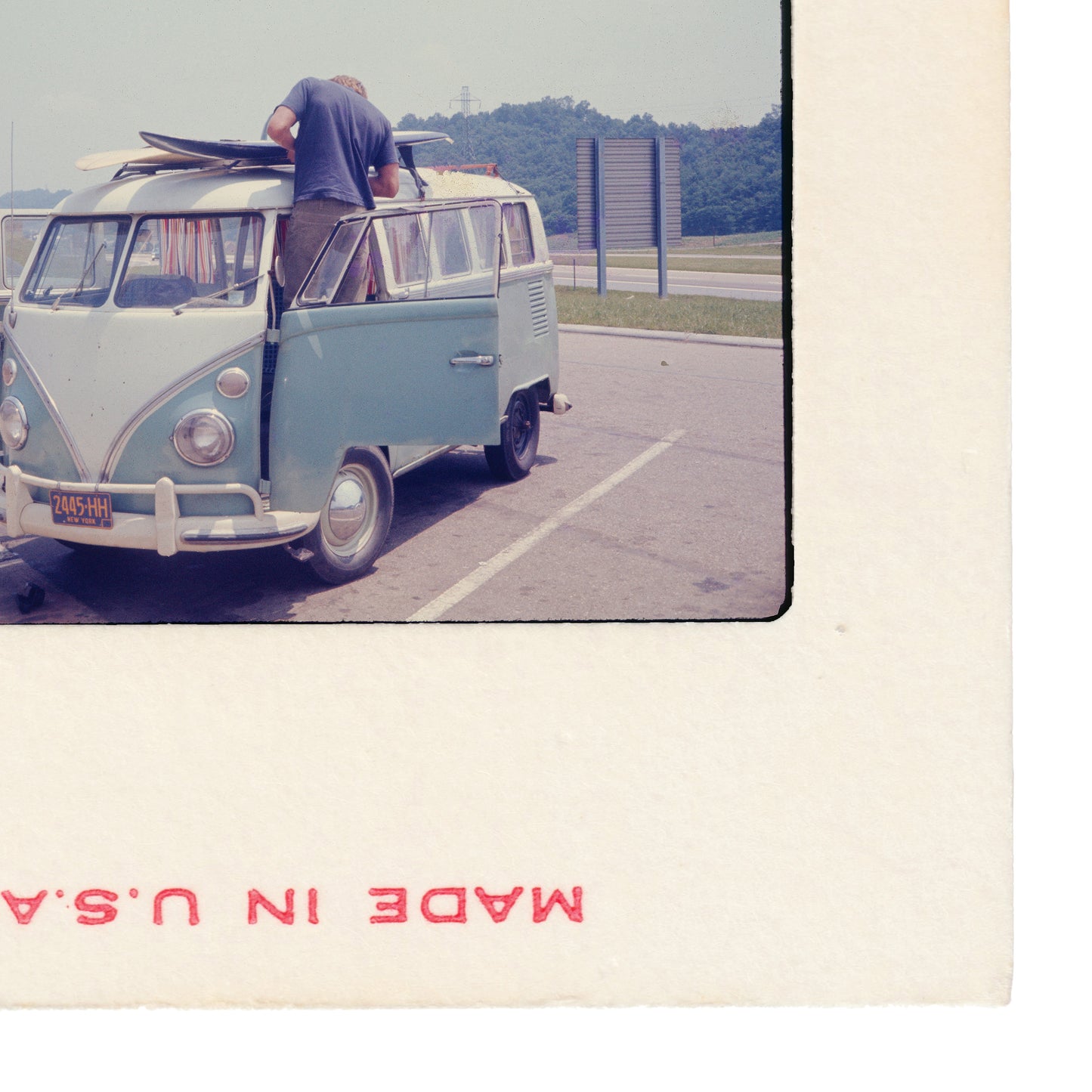 A vintage Volkswagen van with surfboards on top, parked in a lot.