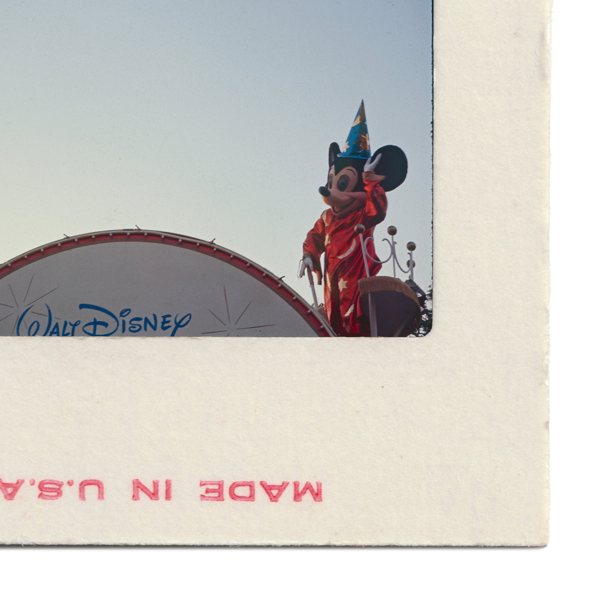 A Mickey Mouse character wearing a red outfit and a blue hat is standing on top of a Disney-themed structure.