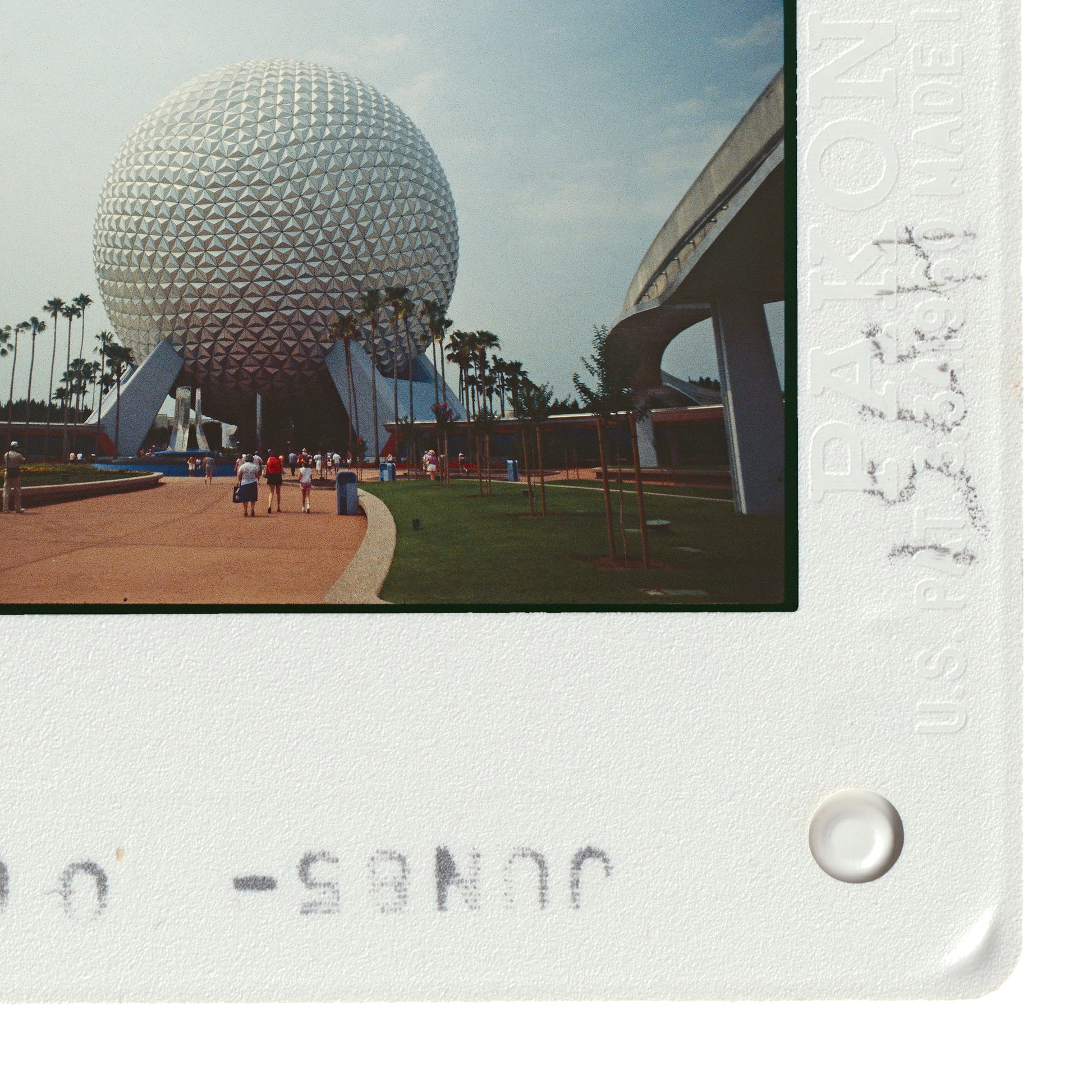 a large, spherical structure with a distinctive geometric design, surrounded by palm trees and a paved walkway.