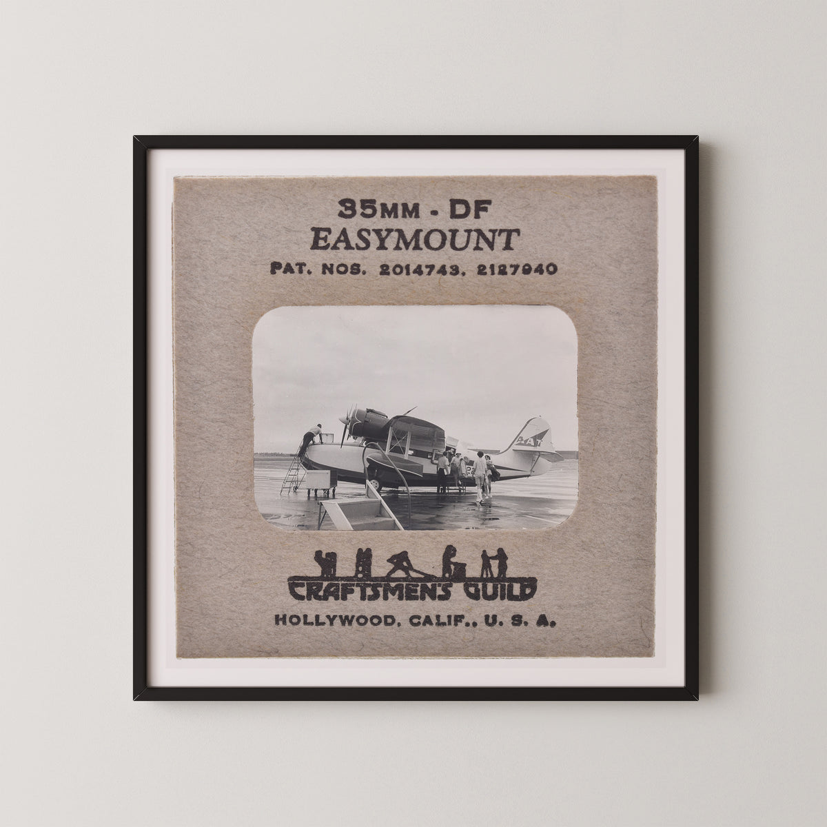 The image is a framed photograph of a vintage airplane, with text and a black and white illustration of people on the airplane.