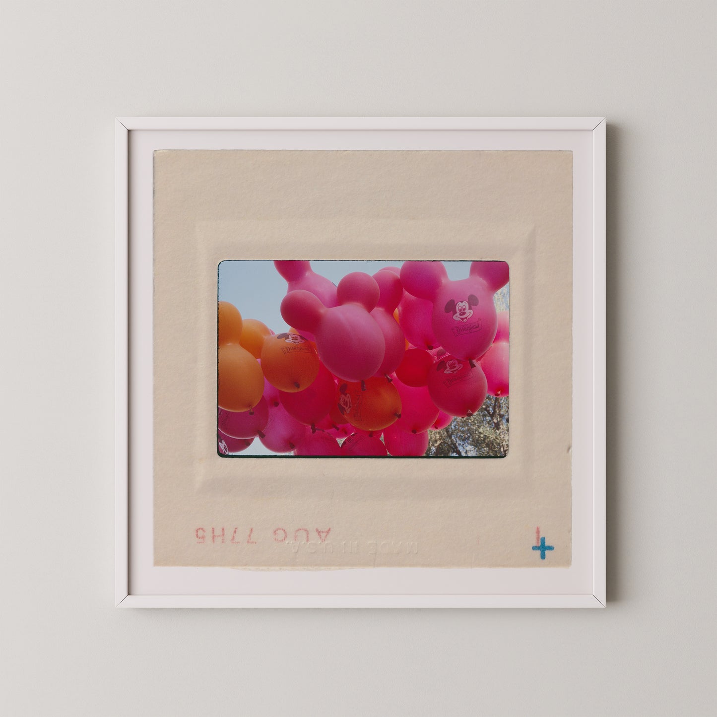 A framed photograph of a bunch of colorful balloons, including pink and orange balloons, floating in the sky.