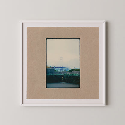 The image is a framed photograph of a bridge, with a cloudy sky in the background.
