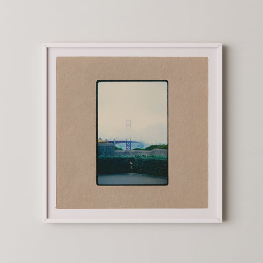 The image is a framed photograph of a bridge, with a cloudy sky in the background.