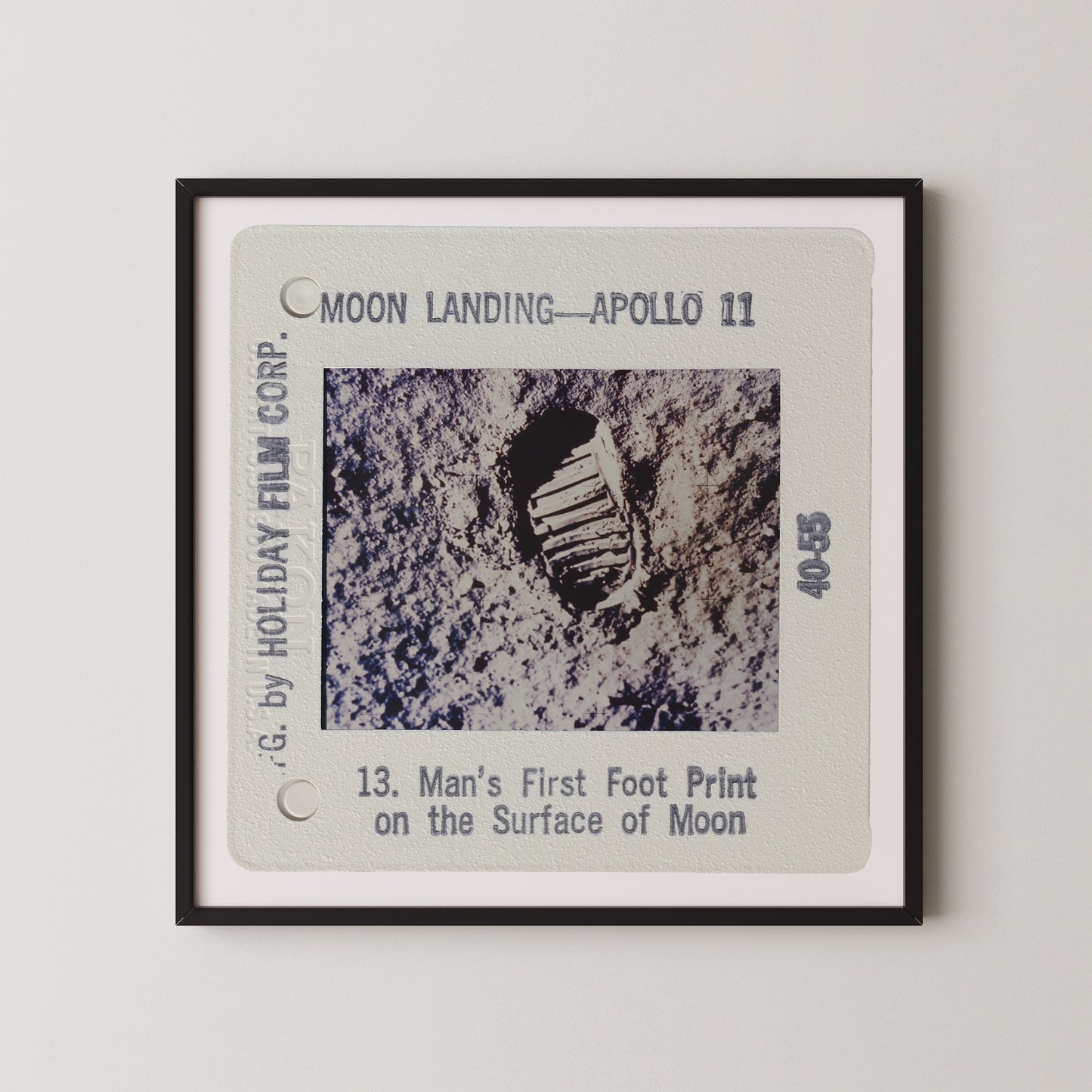 The image is a framed photograph of a man's first footprint on the surface of the Moon, taken during the Apollo 11 mission.