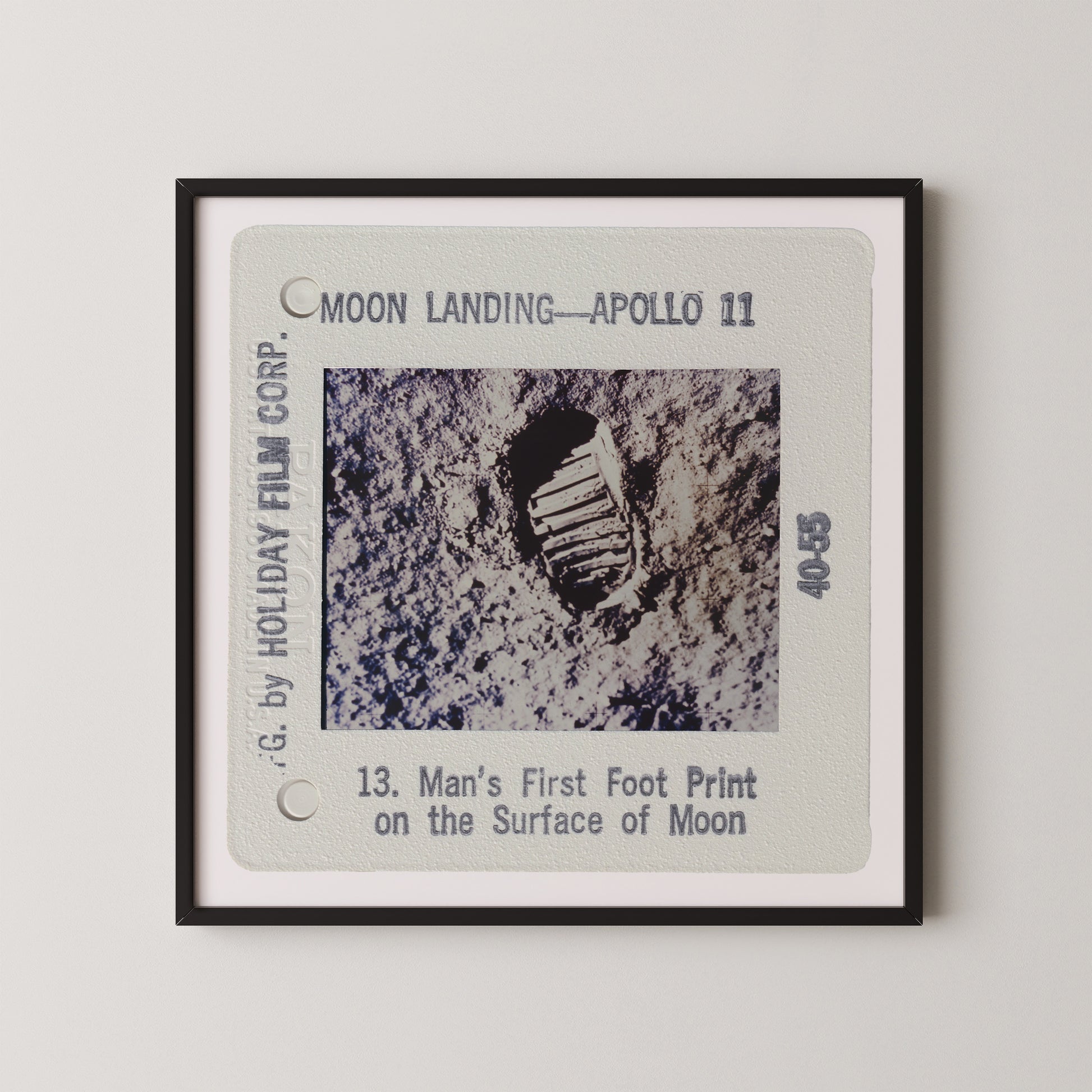 The image is a framed photograph of a man's first footprint on the surface of the Moon, taken during the Apollo 11 mission.