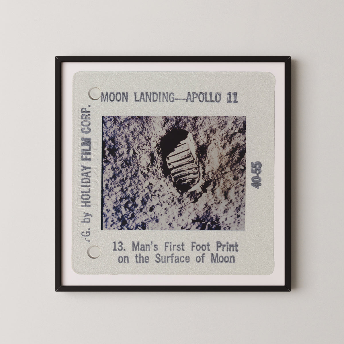 The image is a framed photograph of a man's first footprint on the surface of the Moon, taken during the Apollo 11 mission.