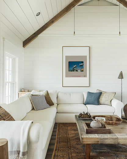 a cozy living room with a large white sectional sofa, a wooden coffee table, and a framed artwork on the wall.