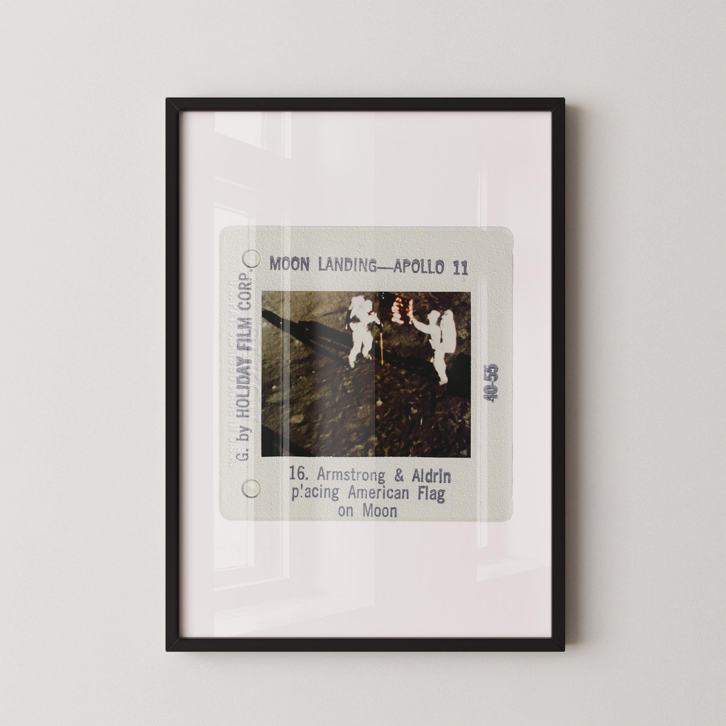The image is a framed photograph of the Apollo 11 moon landing, depicting the two astronauts walking on the surface of the moon.