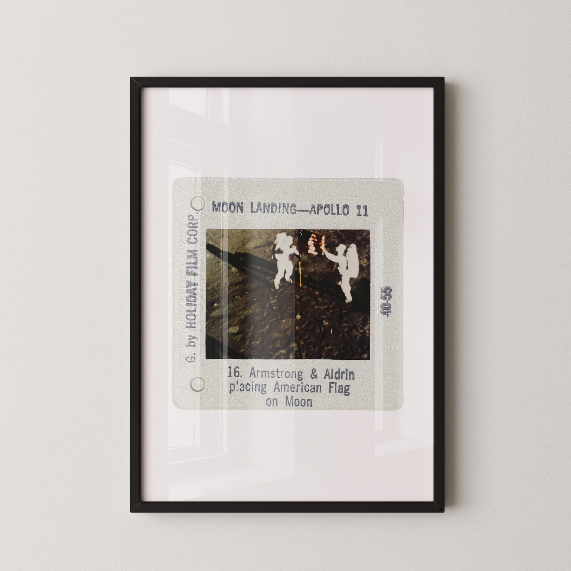 The image is a framed photograph of the Apollo 11 moon landing, depicting the two astronauts walking on the surface of the moon.