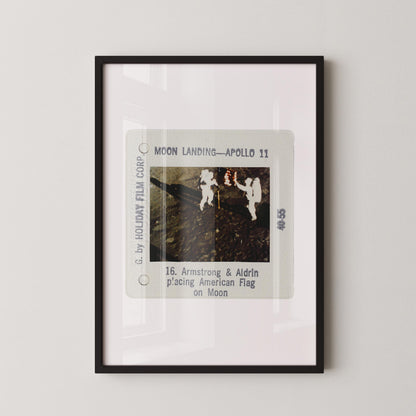 The image is a framed photograph of the Apollo 11 moon landing, depicting the two astronauts walking on the surface of the moon.
