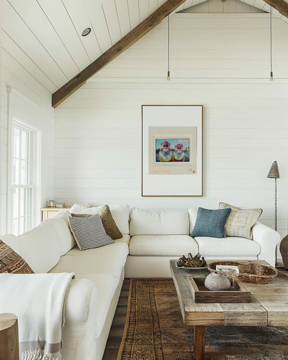 a cozy living room with a white sofa, a wooden coffee table, and a framed artwork on the wall.