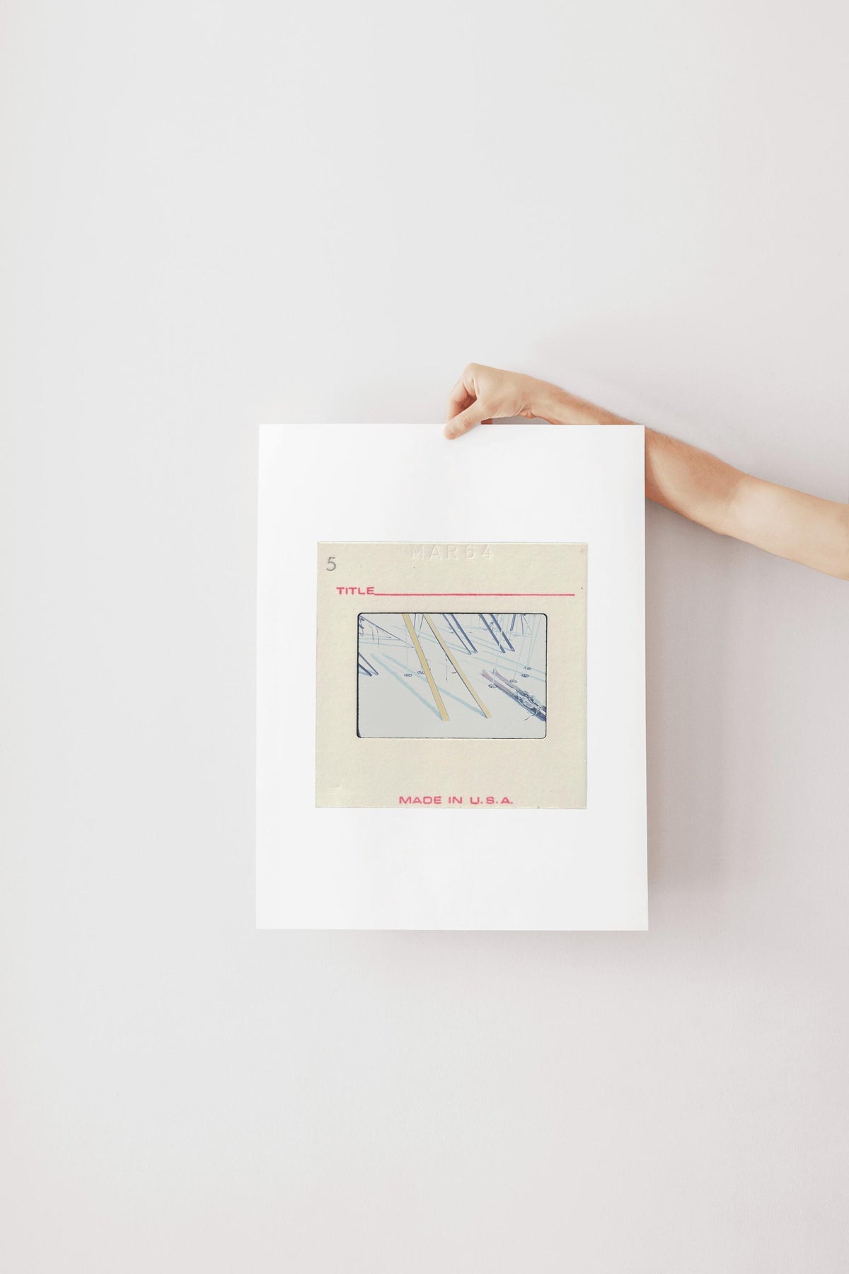 A person's hand is holding a white piece of paper with a framed image of a blue and white abstract design.