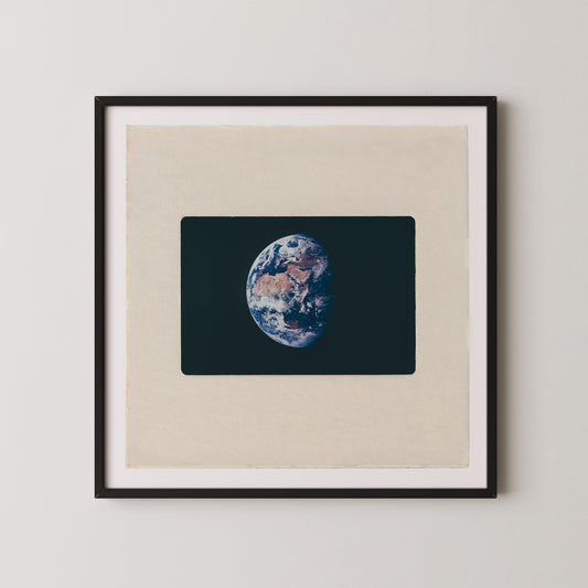 The image is a framed photograph of the Earth, depicting the planet's surface in a detailed and realistic manner.