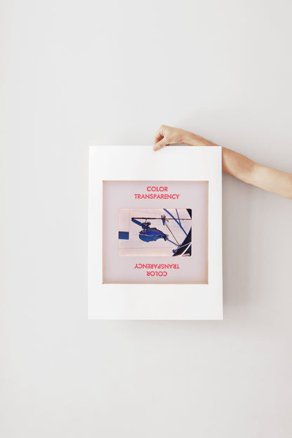A hand is holding a white frame with a framed image of a blue and white abstract artwork.