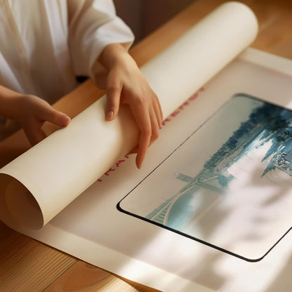 A person's hands are holding a roll of paper, which appears to be a large roll of white paper, and they are placing it on a wooden surface.