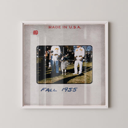 The image is a framed photograph of two men in baseball uniforms standing next to a small goat in a grassy field, with the text "FALL 1955" written below the photograph.