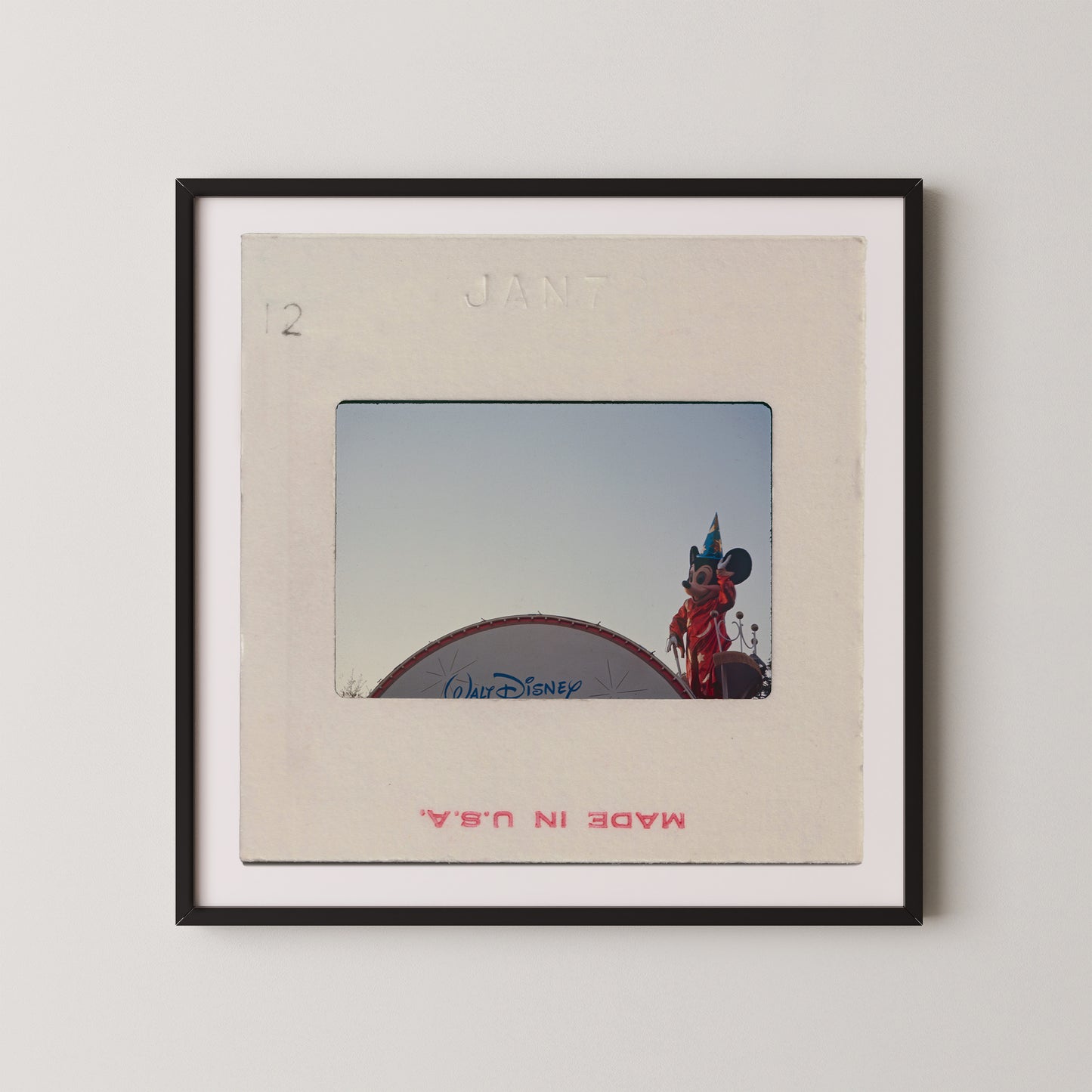 A framed photograph of a Disney character, likely Mickey Mouse, standing on top of a Disney-themed structure.