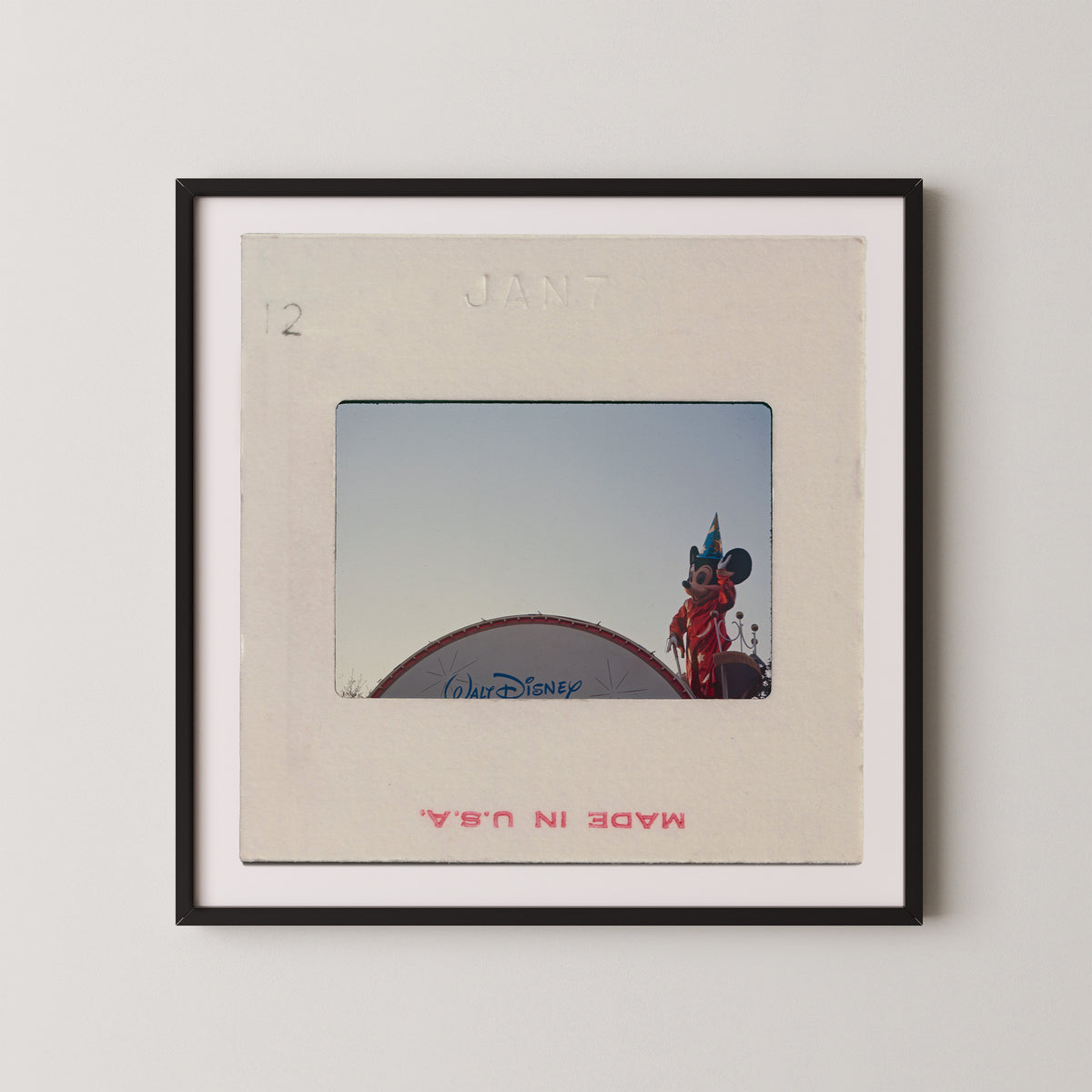 A framed photograph of a Disney character, likely Mickey Mouse, standing on top of a Disney-themed structure.