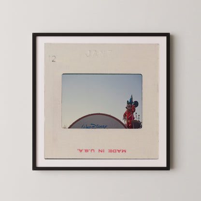 A framed photograph of a Disney character, likely Mickey Mouse, standing on top of a Disney-themed structure.